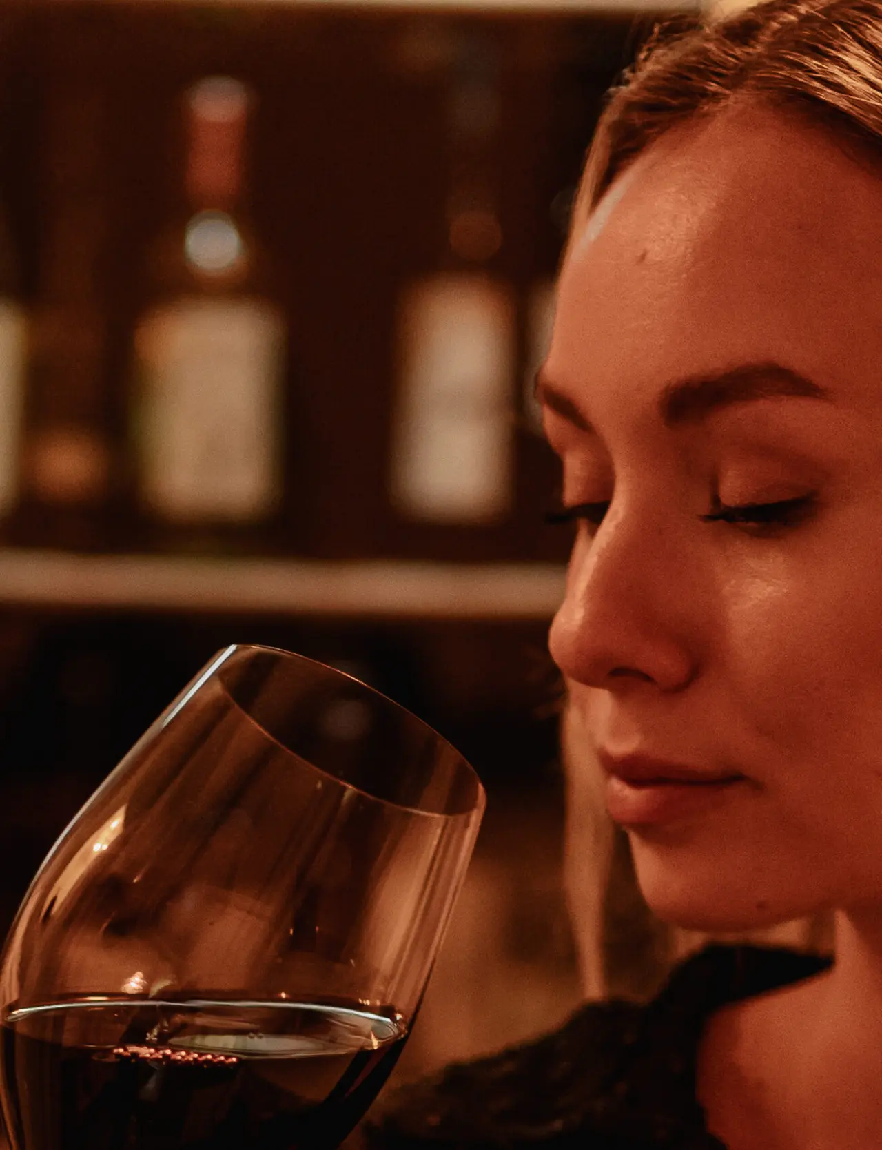 Frau riecht an einem Glas Rotwein in der gemütlichen Weinbar des Schlössl Hotel Kindl.