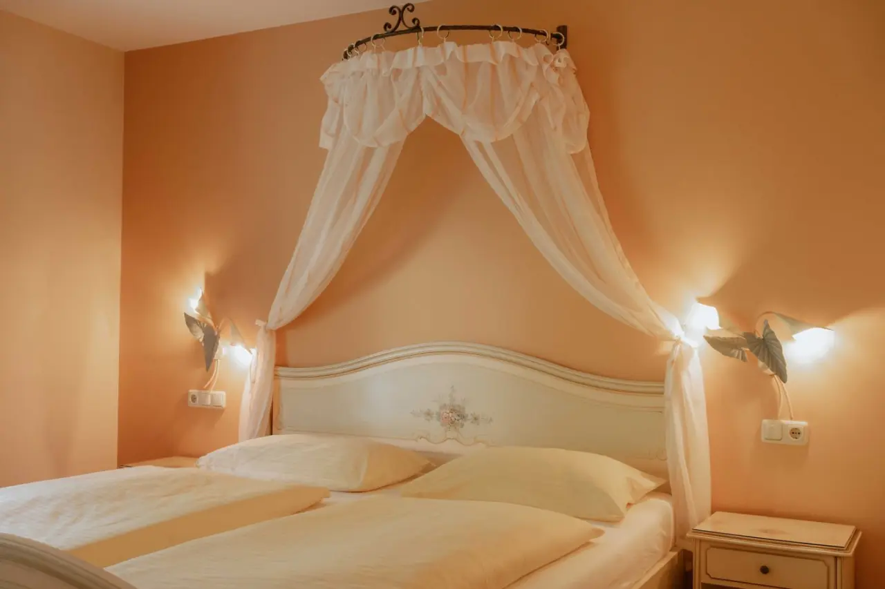 Romantisches Doppelzimmer mit Himmelbett und warmen Farben im Schlössl Hotel Kindl.