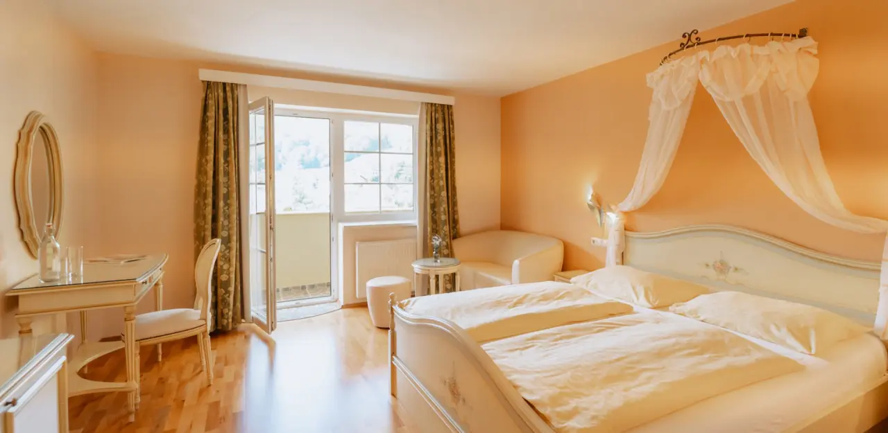 Gemütliches Doppelzimmer mit Balkon und Himmelbett im Schlössl Hotel Kindl, ideal zum Entspannen.