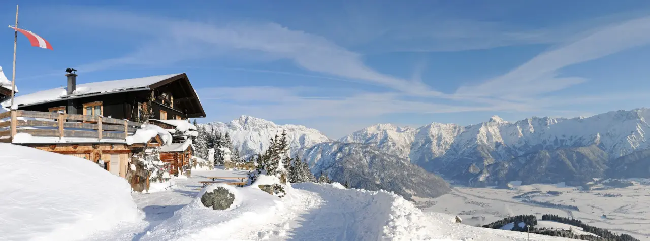 Winterpanorama des Hotel Leonhard mit verschneiter Berghütte und majestätischen Alpen im Hintergrund.