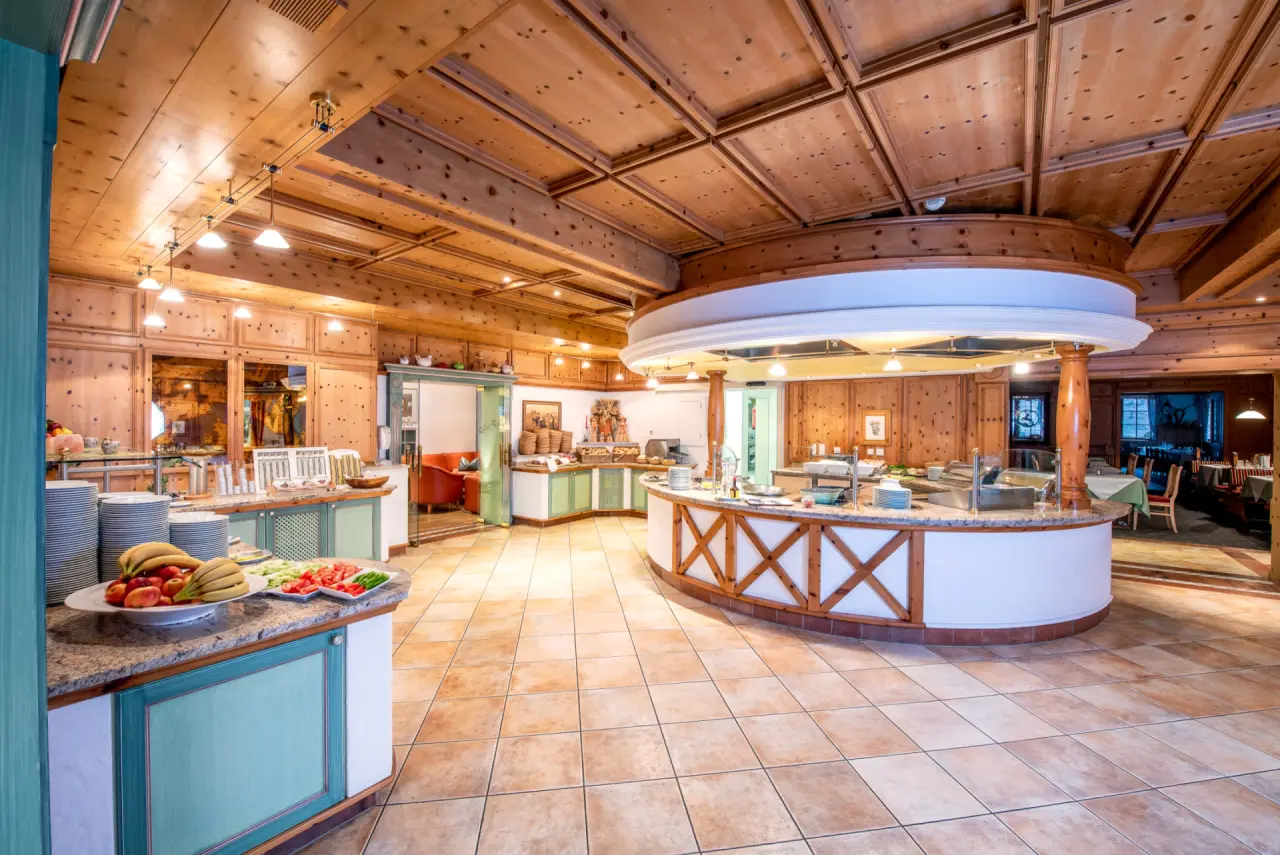Grosszügiges Frühstücksbuffet im Restaurant des Hotel Leonhard mit frischem Obst und traditioneller Holzvertäfelung.