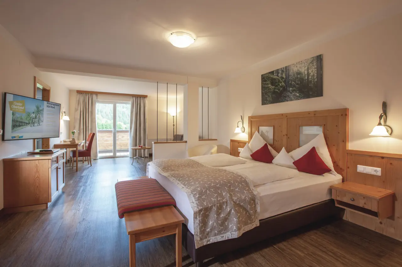 Gemütliches Doppelzimmer im Hotel Truyenhof mit Holzelementen, Balkon und Blick auf die Berglandschaft.