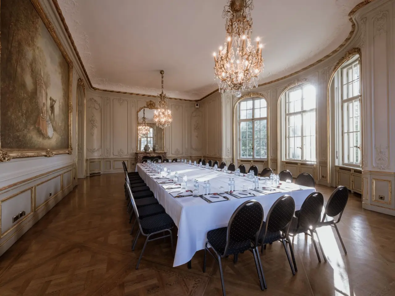 Eleganter Konferenzraum im Patrick Hellmann Schlosshotel mit langer Tafel, Kronleuchtern und hohen Fenstern.