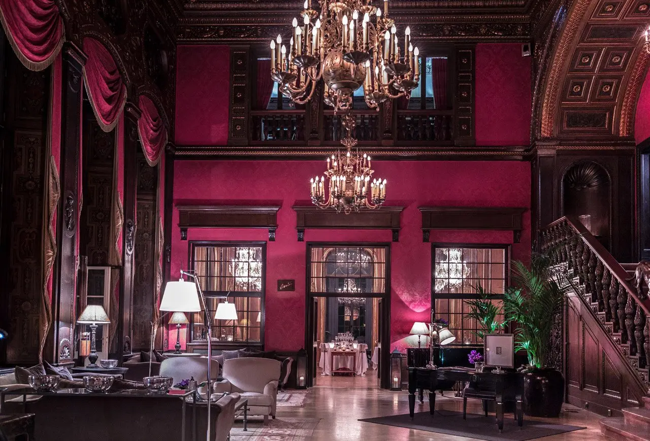 Opulente Lobby mit roten Wänden, Kronleuchtern und klassischer Einrichtung im Patrick Hellmann Schlosshotel.