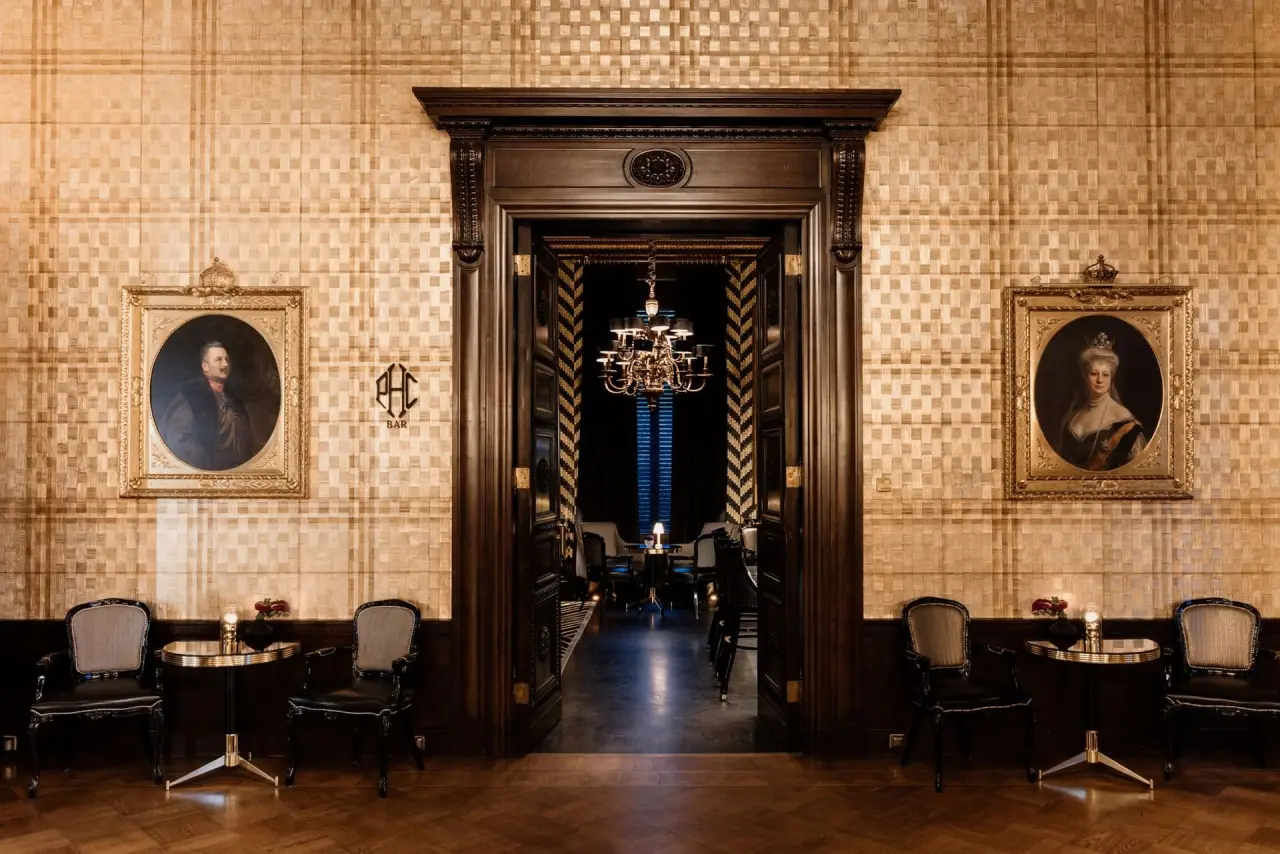 Eingang zur luxuriösen Bar im Patrick Hellmann Schlosshotel mit eleganten Sitzgelegenheiten und historischen Gemälden.