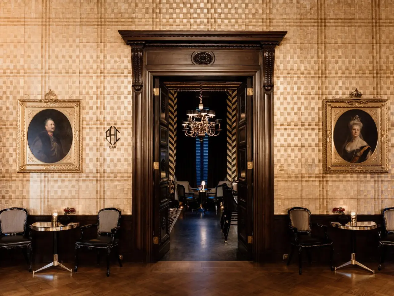 Elegante Bar im Patrick Hellmann Schlosshotel mit klassischer Einrichtung, dunklem Holz und Porträts.