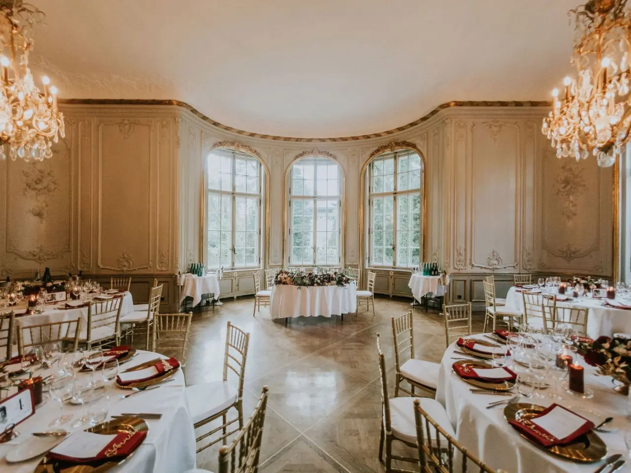 Elegantes Festsaal im Patrick Hellmann Schlosshotel mit festlich gedeckten Tischen, Kronleuchtern und großen Fenstern.
