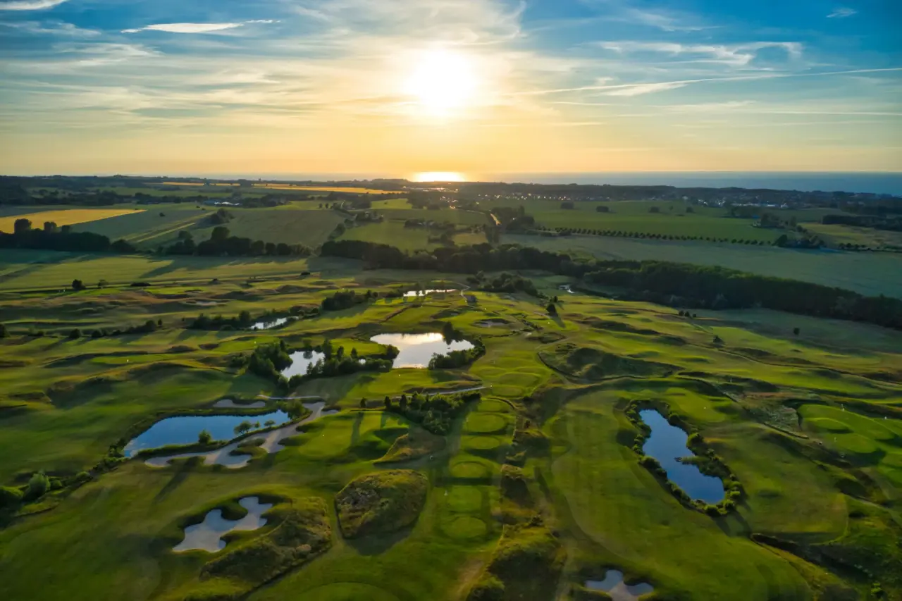 Panoramablick auf den Golfplatz des Grand Hotel Heiligendamm bei Sonnenuntergang mit Ostsee im Hintergrund.