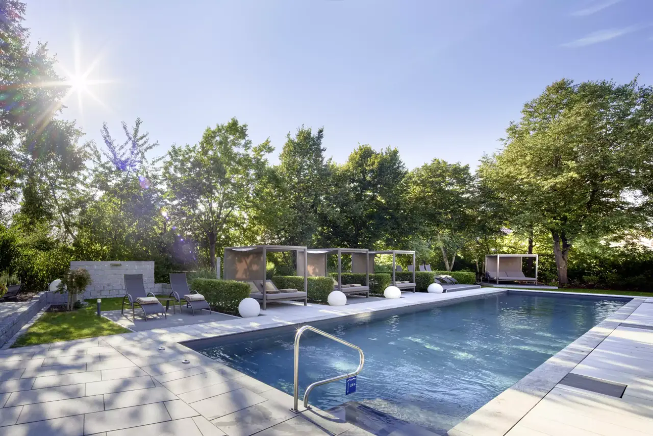 Aussenpool mit modernen Sonnenliegen und Cabanas im Garten des Götzfried**** Kultur- und Spahotels.