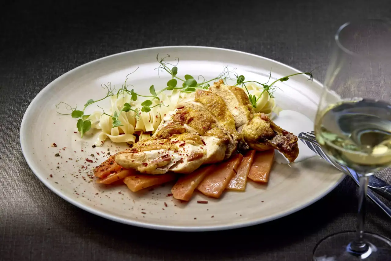 Exquisites Hähnchengericht mit Nudeln und Gemüse, serviert mit Weißwein im Restaurant des Götzfried Spahotels.
