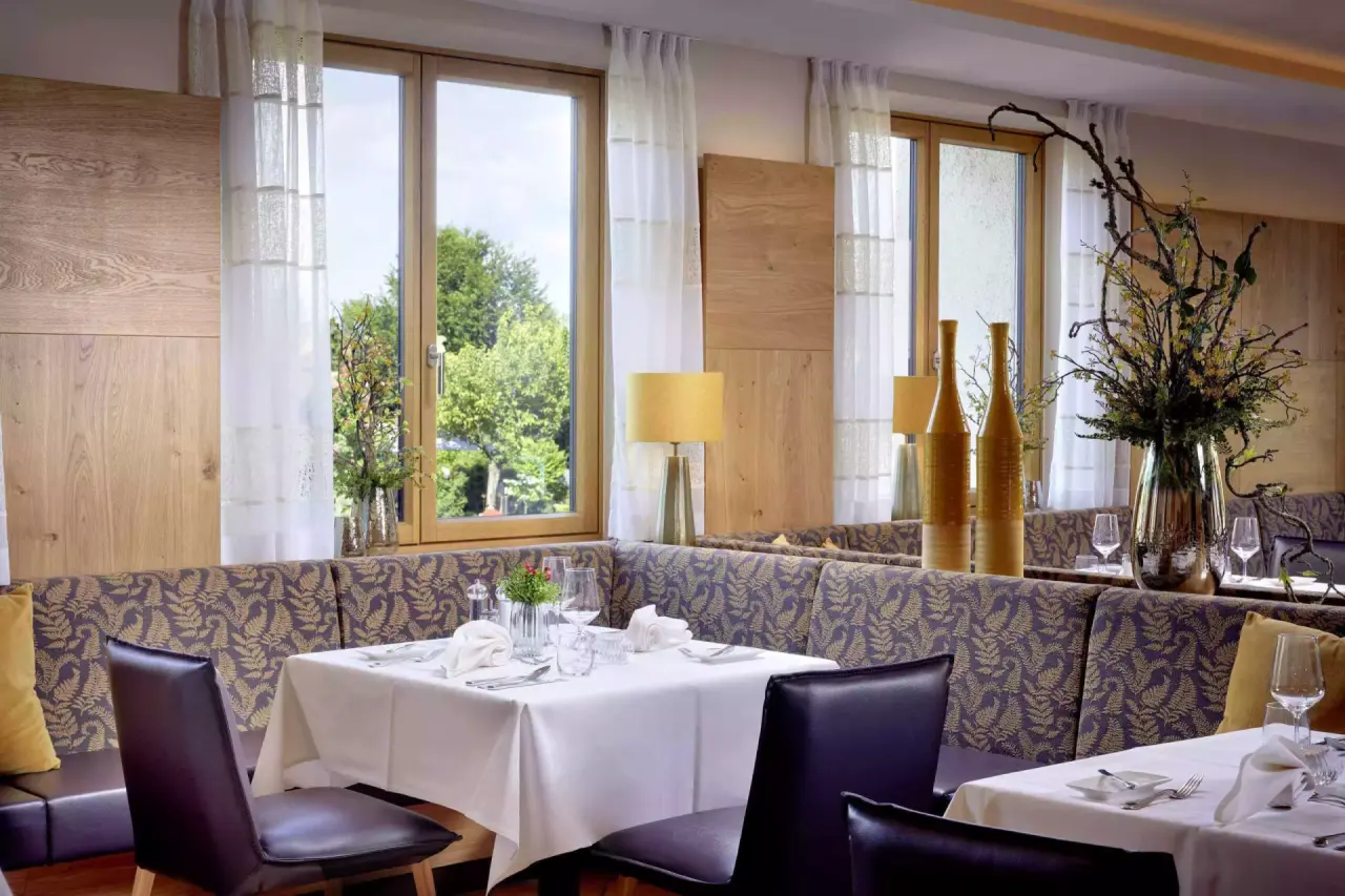 Gemütlicher Restaurantbereich mit elegant gedeckten Tischen und Blick ins Grüne im Götzfried**** Kultur- und Spahotel.