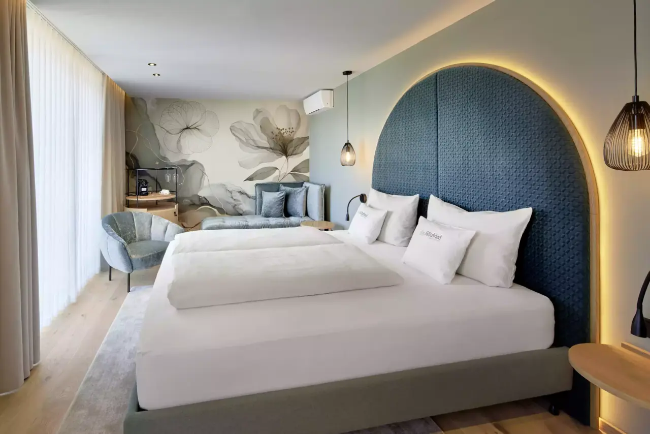 Modernes Doppelzimmer mit stilvollem Kopfteil und Sitzbereich im Das Götzfried**** Kultur- und Spahotel.