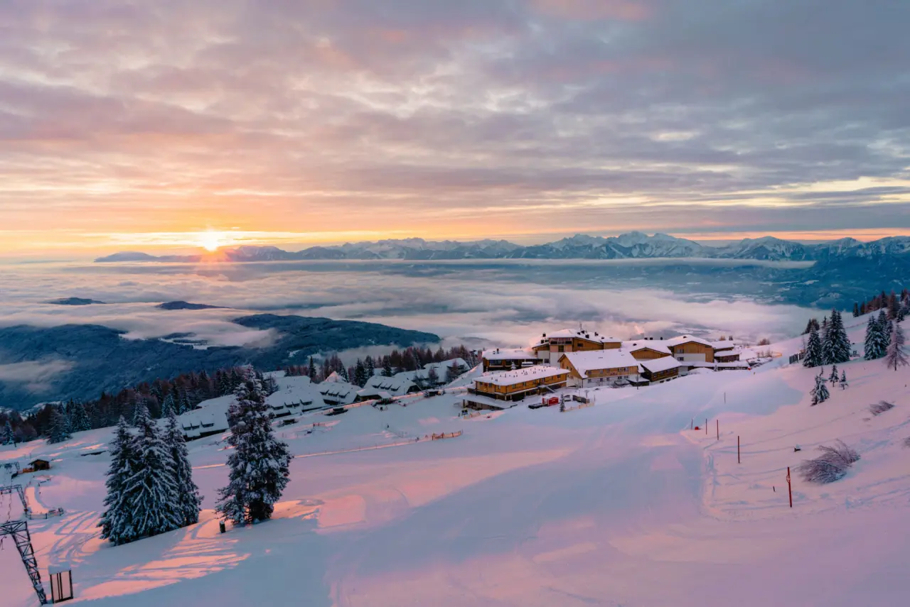 Malerischer Sonnenaufgang über dem Feuerberg Mountain Resort mit verschneiter Landschaft und Wolkenmeer.
