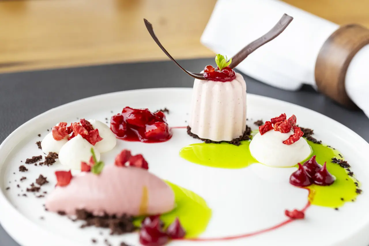 Exquisites Erdbeer-Dessert mit Sahne und Schokocrumble, kunstvoll angerichtet im Restaurant des Strandhotel Dünenmeer.