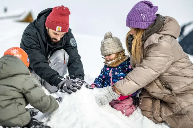 Familie beim Schneemannbauen im Winterurlaub im Kleinwalsertaler Rosenhof.