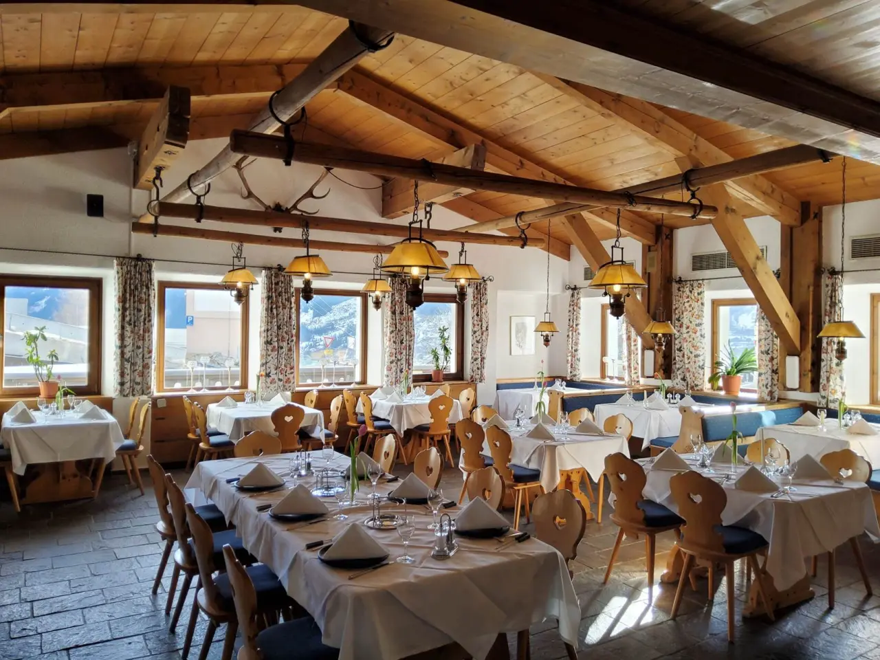 Gemütliches Restaurant im alpinen Stil mit Holzbalken, eingedeckten Tischen und Bergblick im Hotel Goldried.