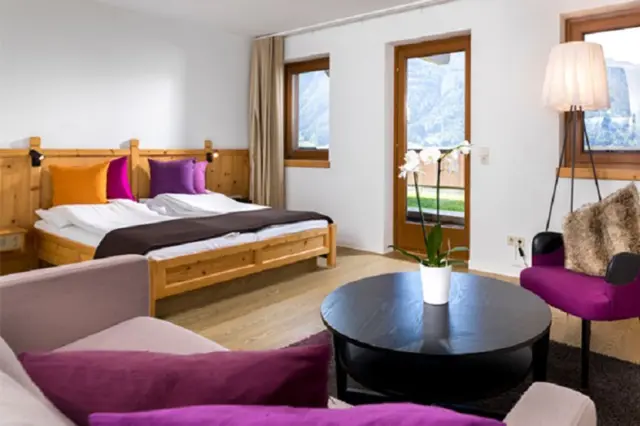Gemütliches Hotelzimmer im Hotel Goldried mit Doppelbett, Sitzbereich und Balkon mit Bergblick.