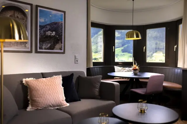 Gemütlicher Wohnbereich mit Sofa, Esstisch und Bergblick in einer Suite des Hotel Goldried.