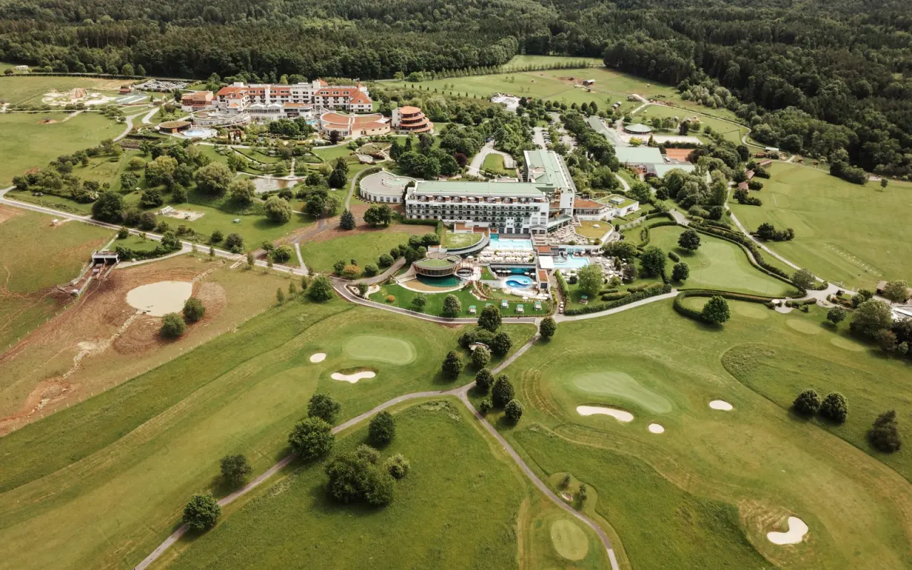 Panoramablick auf das Hotel Reiters Finest Family Resort mit weitläufiger Anlage, Pools, Golfplatz und Wald.