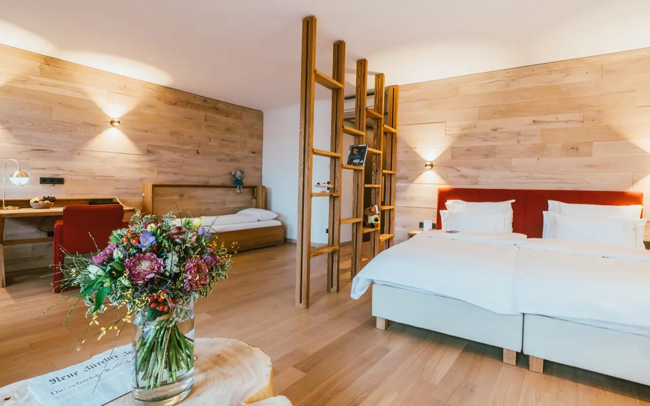 Geräumiges Familienzimmer im Hotel Reiters Finest Family mit Doppelbett, Einzelbett und Holzelementen.