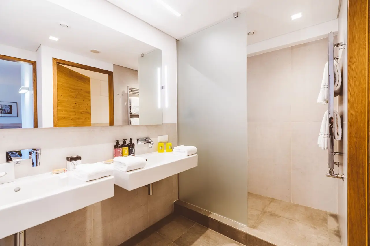 Modernes Badezimmer mit Doppelwaschbecken und begehbarer Dusche im Hotel Reiters Finest Family.