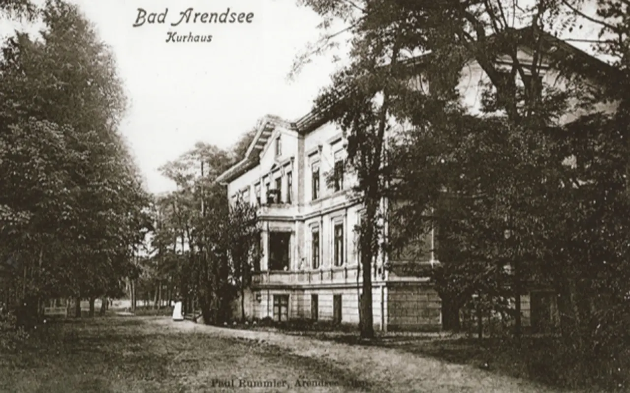 Historische Schwarz-Weiß-Ansicht des Kurhauses Bad Arendsee, umgeben von Bäumen. Frühe Aufnahme des Hotels 'Haus am See'.