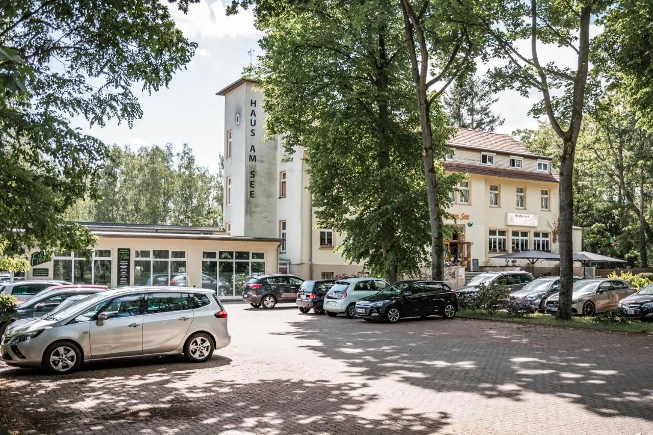 Aussenansicht des Wellness-& Sporthotels Haus am See mit Parkplatz und grüner Umgebung an einem sonnigen Tag.