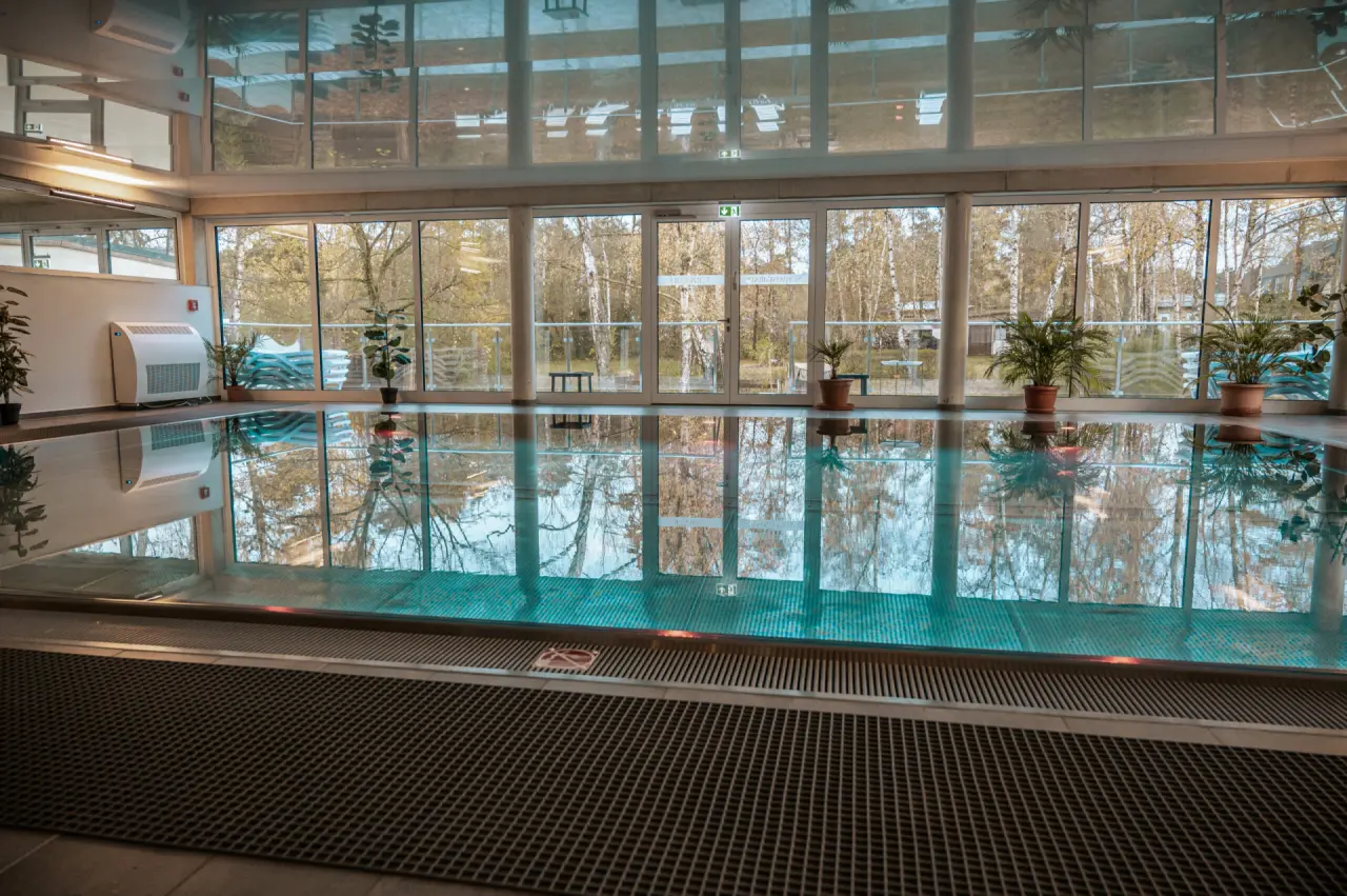Großzügiger Innenpool mit Tageslicht und Blick auf die umliegende Natur im Wellness- & Sporthotel 'Haus am See'.