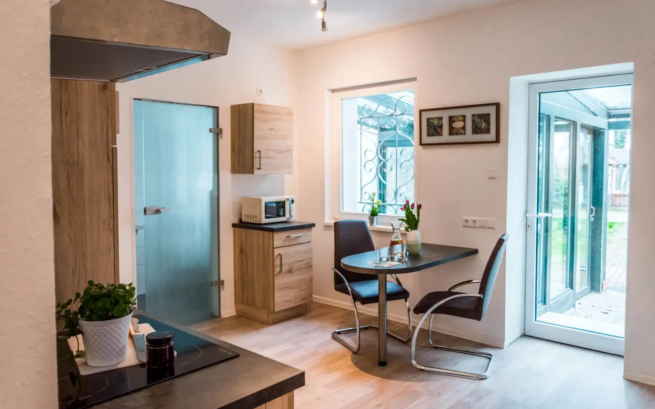 Kleine Küchenzeile mit Esstisch und Blick ins Grüne in einem Zimmer des Wellness- & Sporthotels 'Haus am See'.