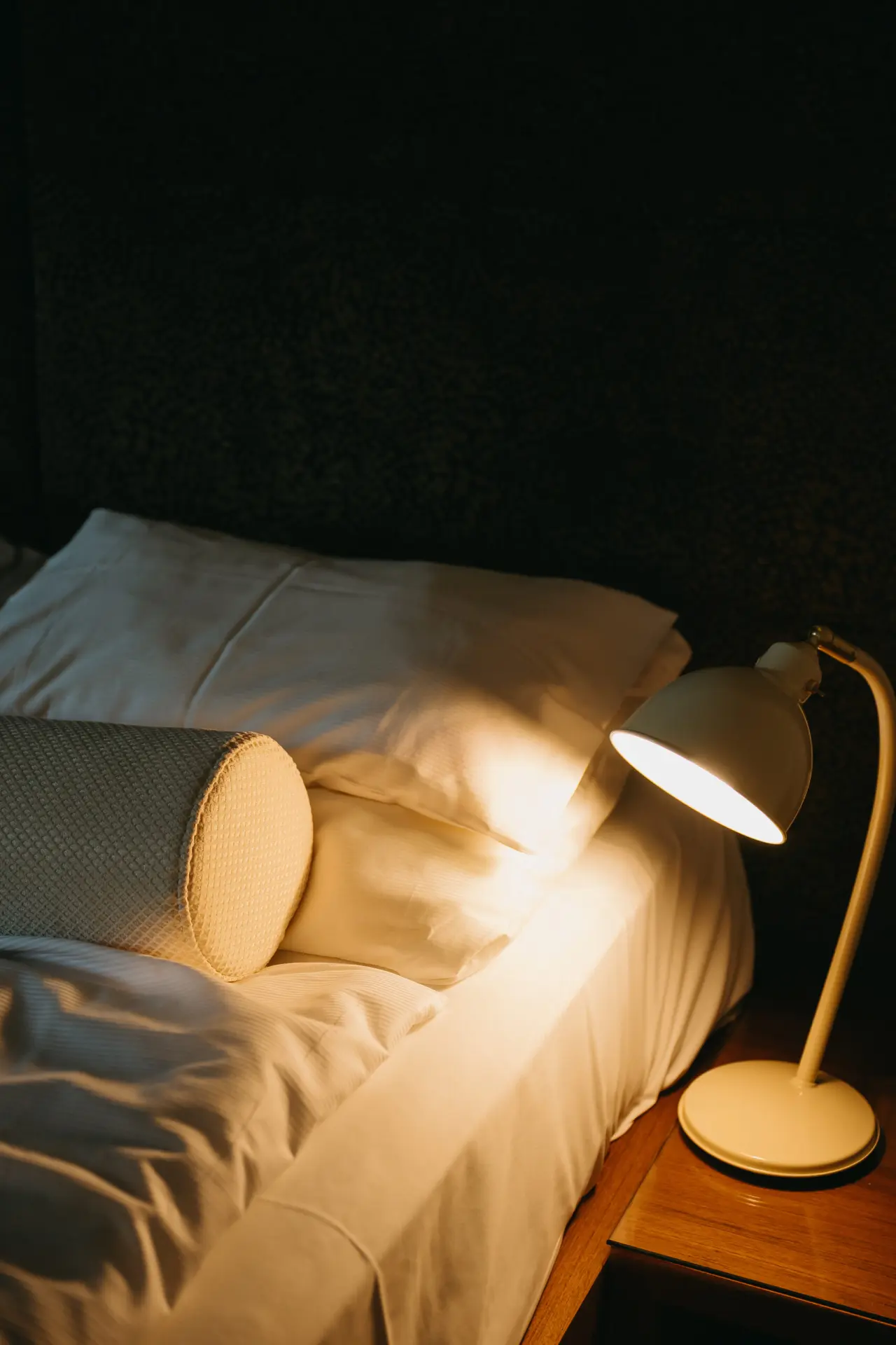 Detailansicht eines gemütlichen Hotelzimmers im Hotel Schlafgut mit Nachttischlampe und weichem Bett.