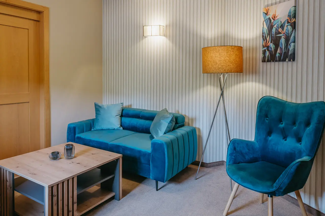 Gemütlicher Wohnbereich mit blauem Sofa und Sessel in einem Zimmer des Hotel Schlafgut