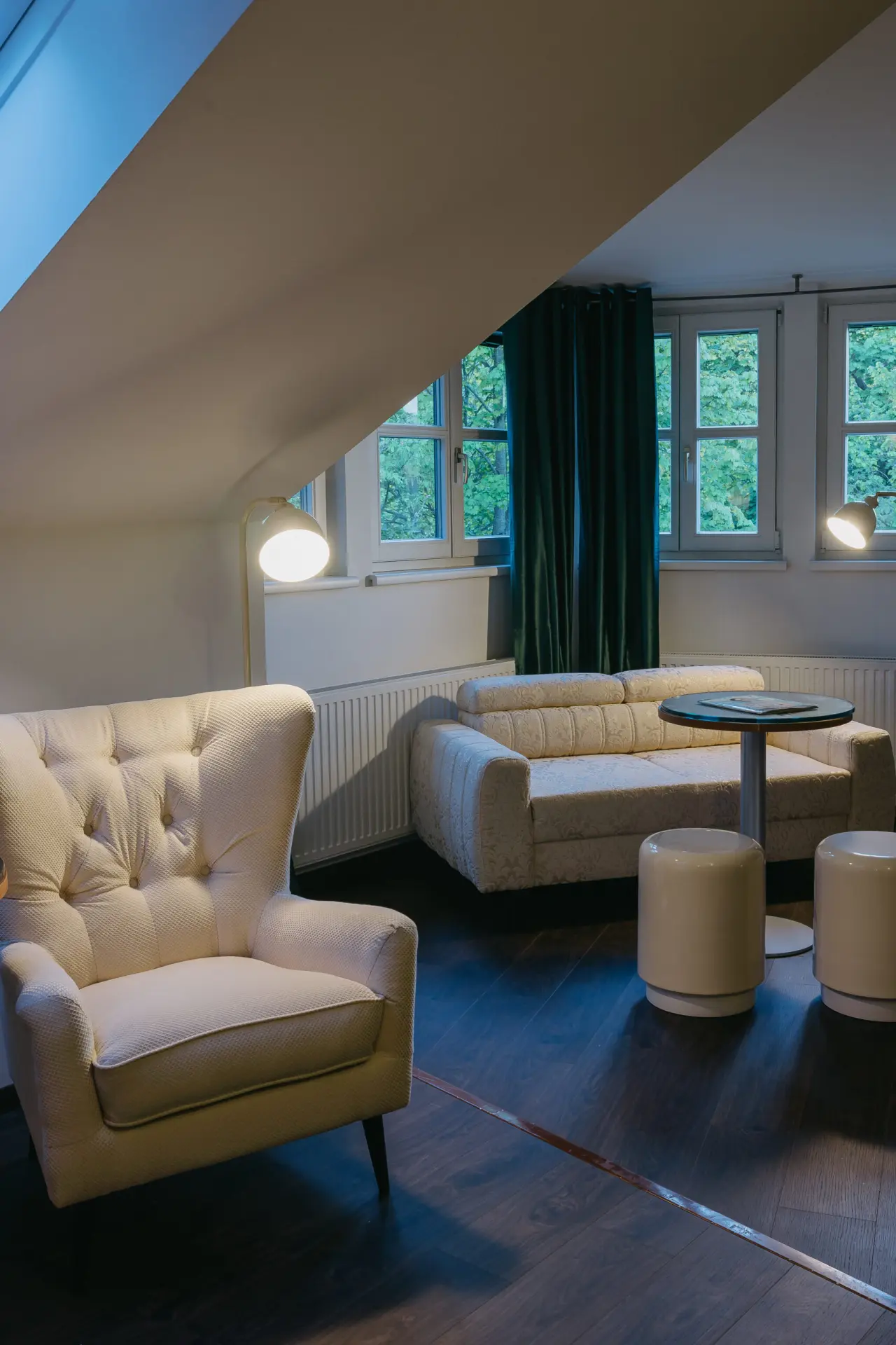 Gemütlicher Sitzbereich mit Sessel, Sofa und Fenstern im Dachgeschoss des Hotel Schlafgut.
