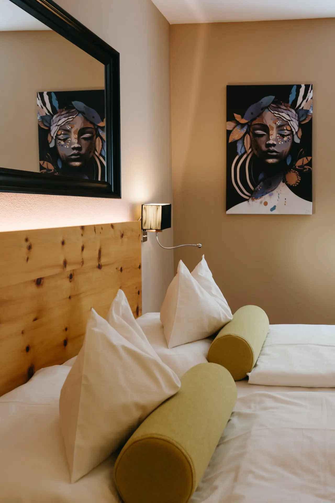 Gemütliches Doppelzimmer im Hotel Schlafgut mit Holzkopfteil, bequemen Betten und moderner Kunst an der Wand.