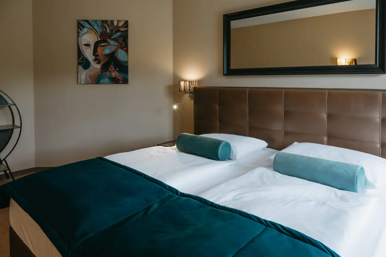 Gemütliches Doppelzimmer im Hotel Schlafgut mit braunem Kopfteil, türkisen Akzenten und moderner Wandkunst.