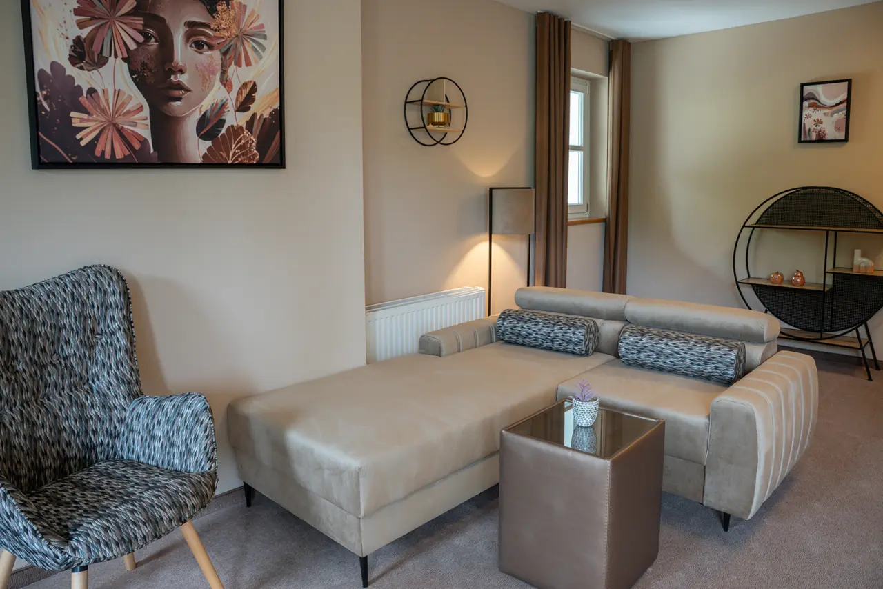 Gemütlicher Wohnbereich mit modernem Sofa und Sessel im Hotel Schlafgut. Ideal zum Entspannen.