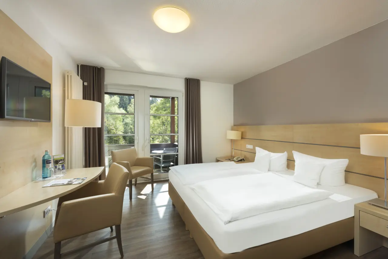 Helles Doppelzimmer mit Balkon und Waldblick im relexa hotel Harz-Wald, ideal für einen entspannten Aufenthalt.