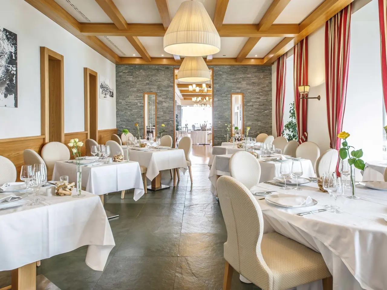 Elegantes Restaurant im Kurhaus Cademario mit stilvoll gedeckten Tischen und Blick in den Barbereich.