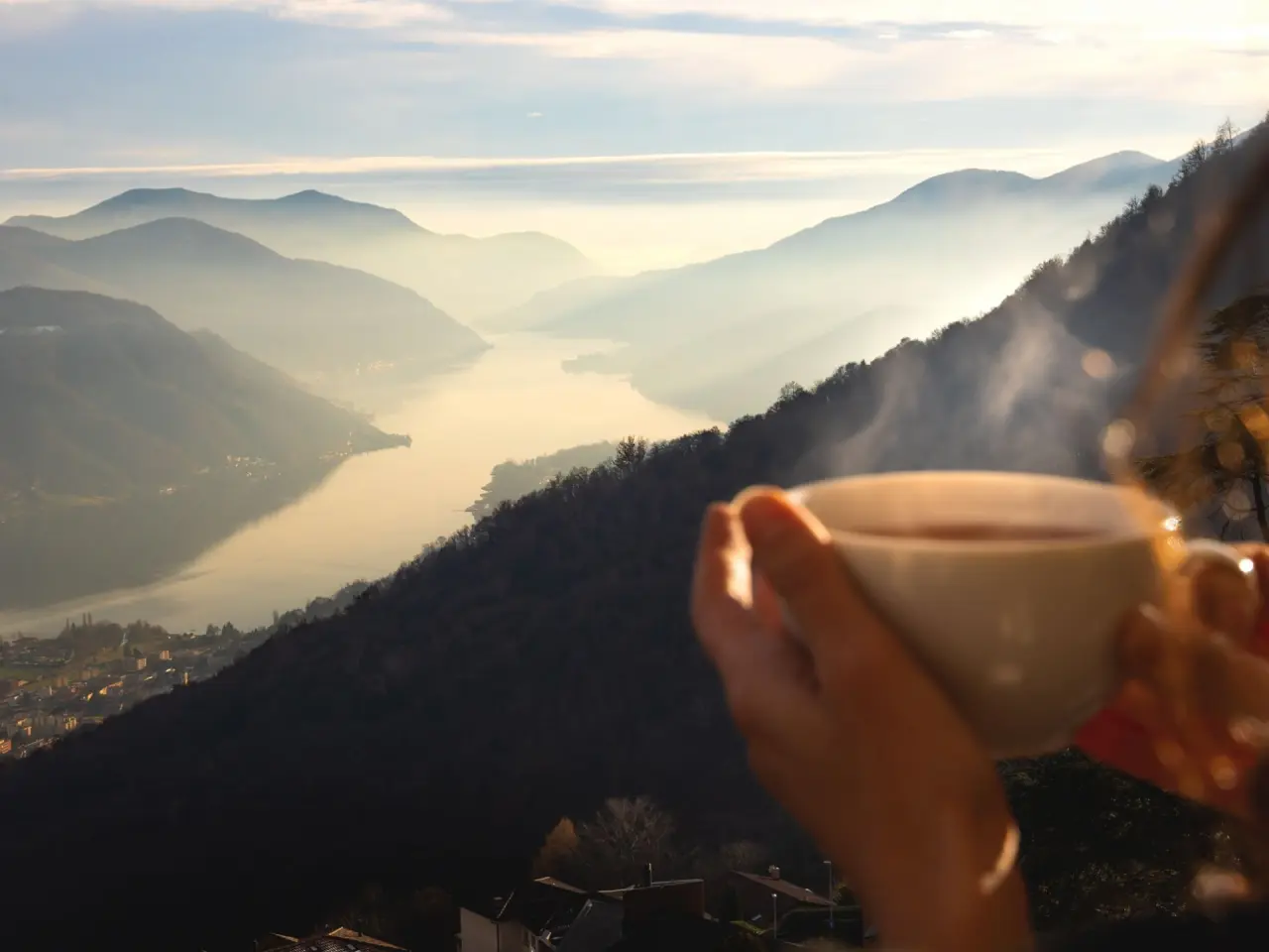Malerischer Panoramablick auf den Luganersee und die Berge vom Kurhaus Cademario, genossen mit einer dampfenden Tasse.