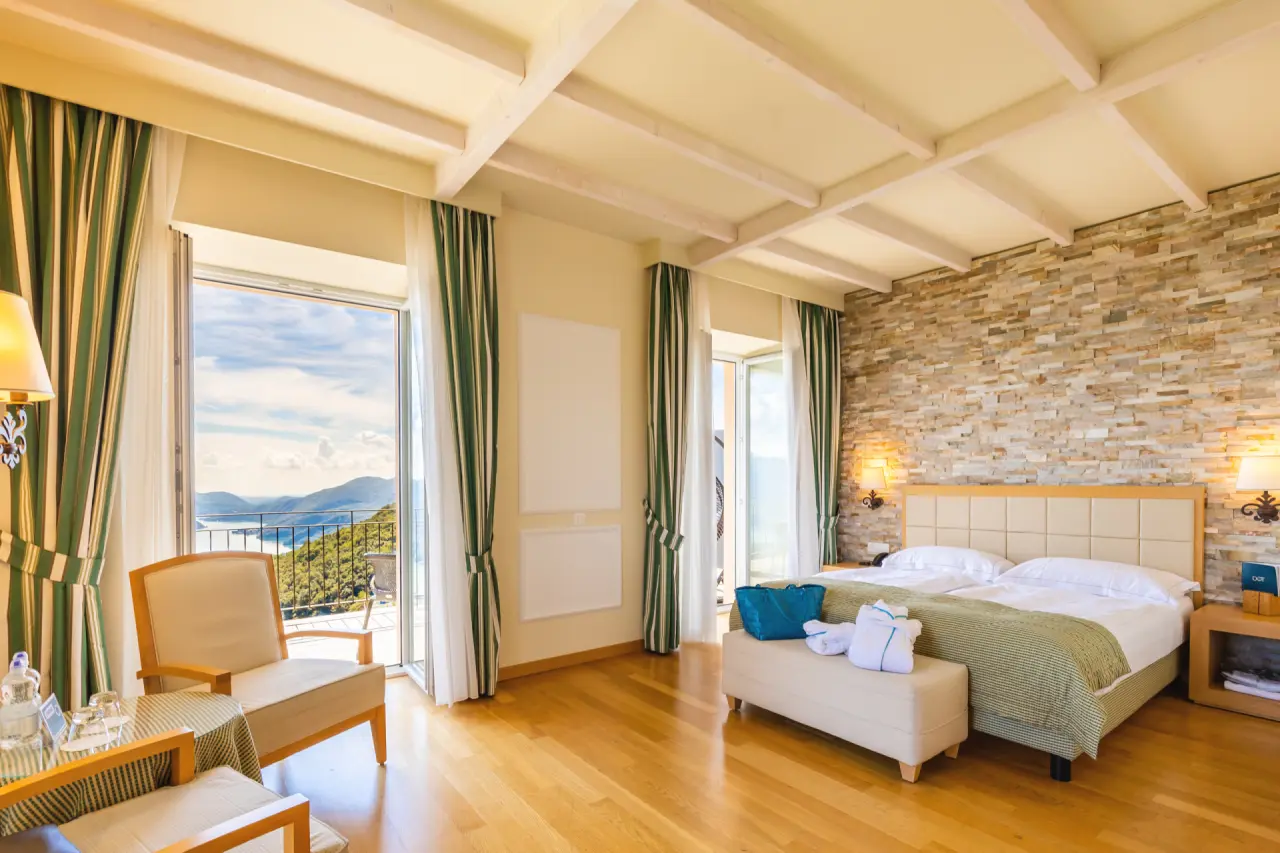 Geräumiges Hotelzimmer mit Doppelbett, Balkon und malerischem Seeblick im Kurhaus Cademario.
