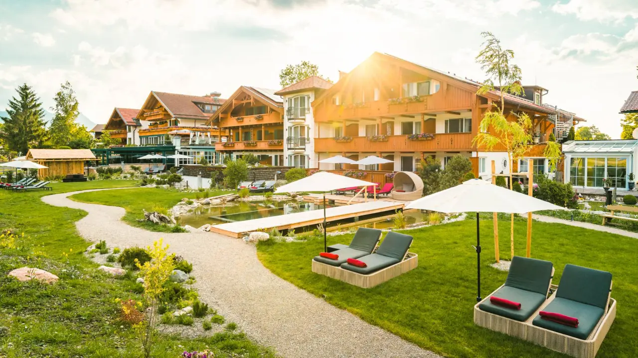 Wellnesshotel Das Rübezahl: Idyllischer Garten mit Naturpool, Liegewiesen und traditionellen Gebäuden.