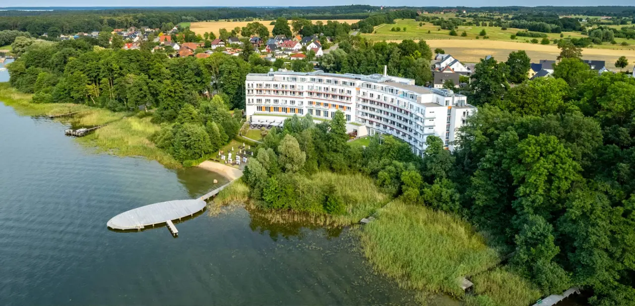 Luftaufnahme des Seehotel Fleesensee direkt am Ufer des Fleesensees mit eigenem Badestrand und Steg, umgeben von Natur.