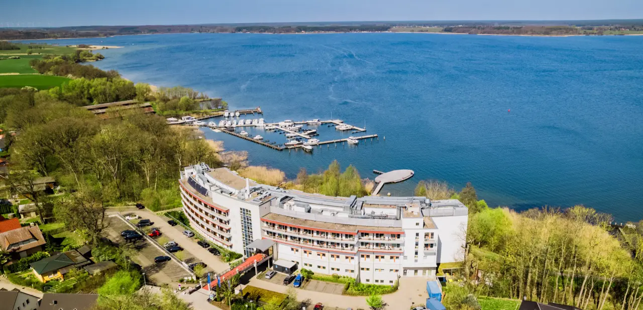 Luftaufnahme des Seehotel Fleesensee direkt am blauen Fleesensee mit eigener Marina und grüner Umgebung.