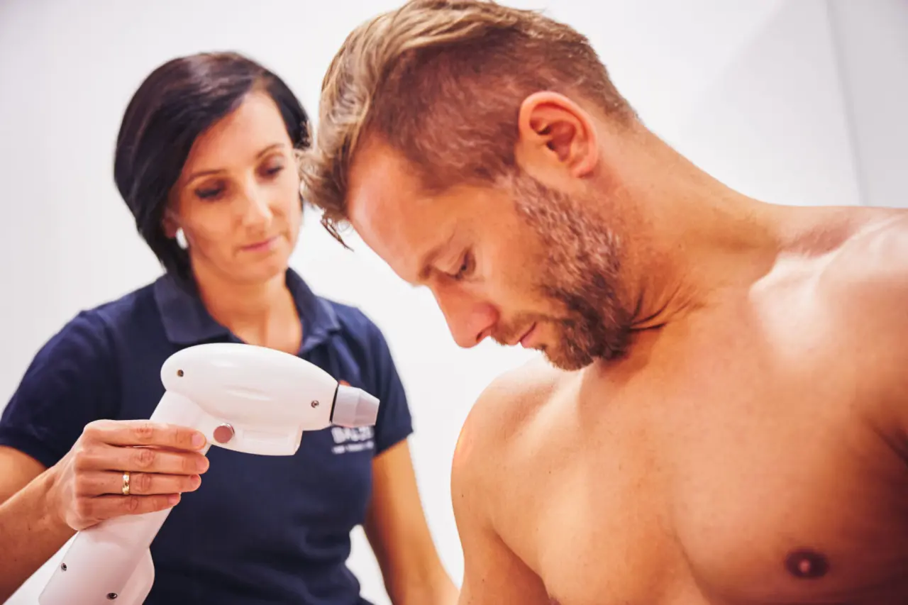 Therapeutische Behandlung mit Kältetherapiegerät an der Schulter eines Mannes im Spa des Hotel Lebensquell.