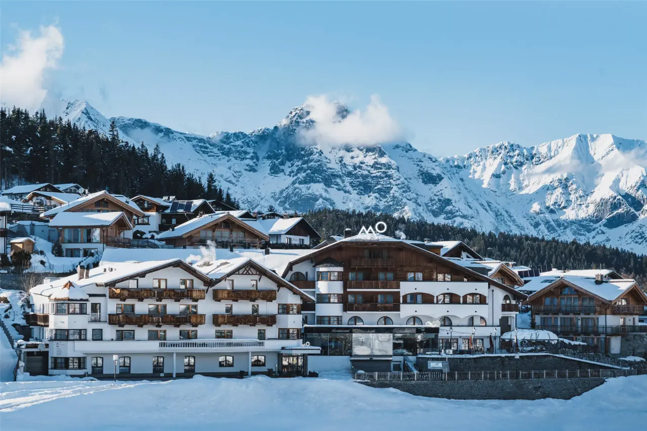 Winterliche Aussenansicht des Mountains Hotel mit verschneiten Dächern und majestätischem Bergpanorama in den Alpen.