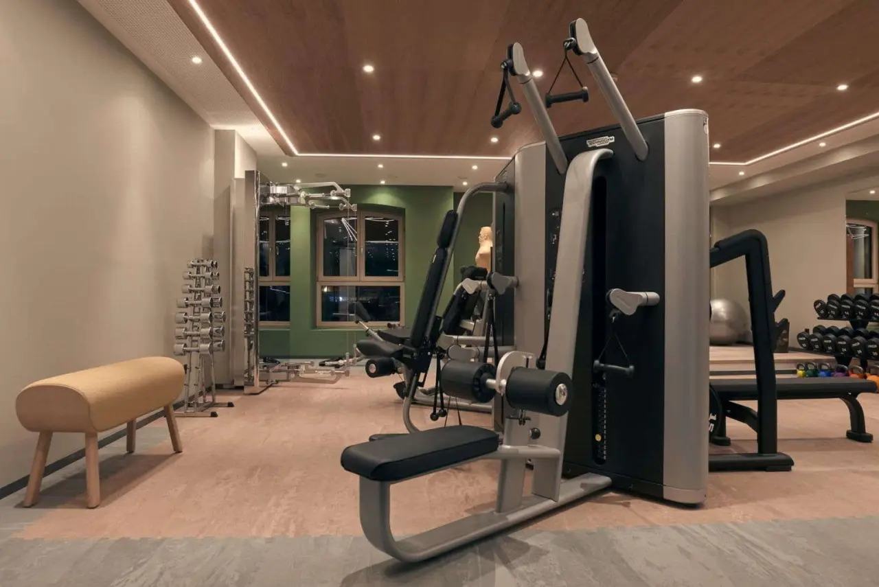 Moderner Fitnessraum mit hochwertigen Technogym-Geraeten und Hanteln im Mountains Hotel.