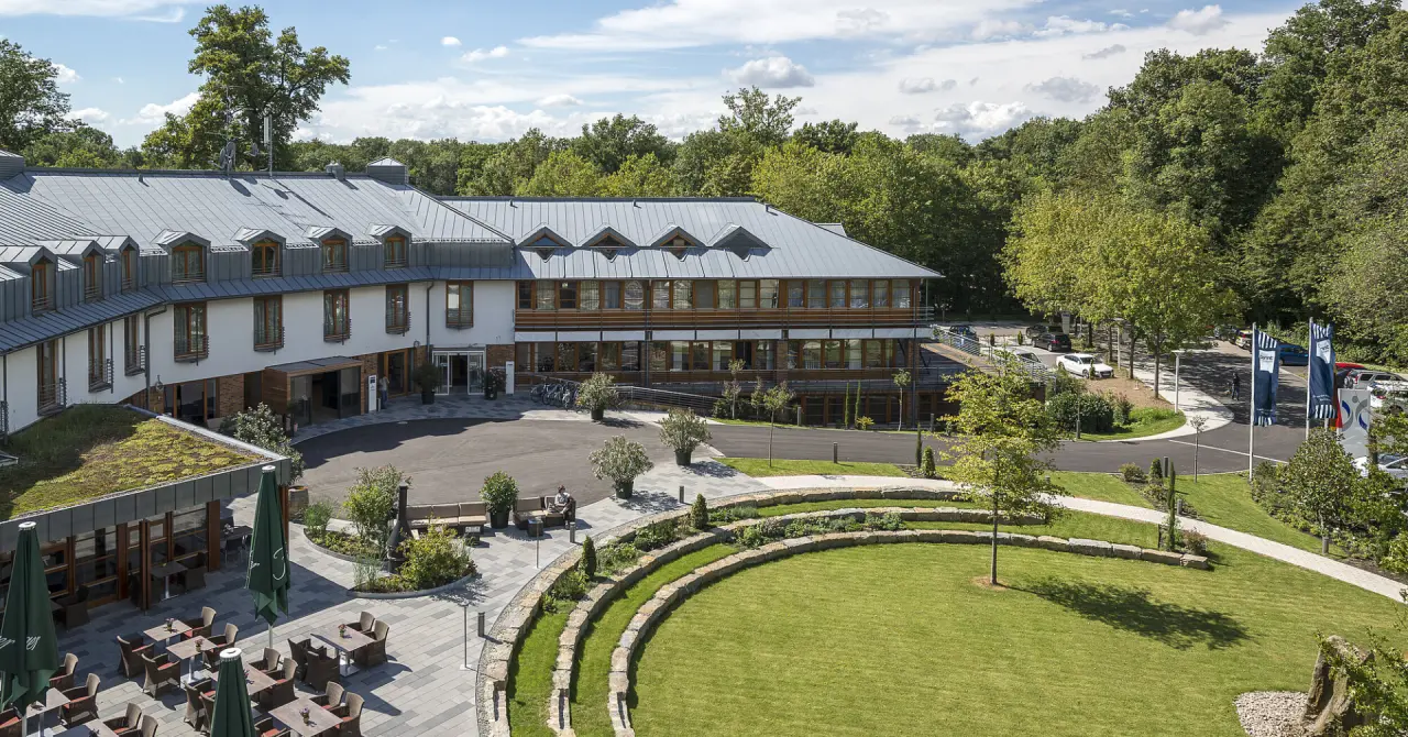 Aussenansicht des Dorint An den Thermen Hotels mit begrünter Dachterrasse, Restaurant-Terrasse und weitläufigem Gartenbereich.