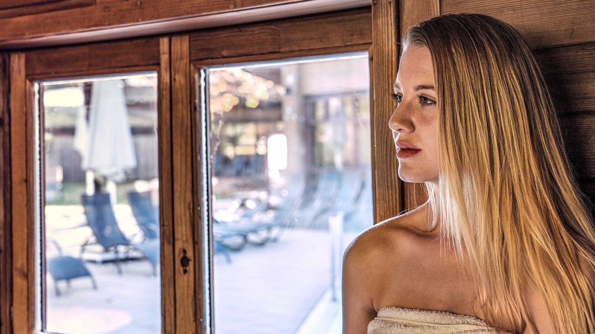 Dorint An den Thermen in Freiburg-Süd – Frau entspannt in der Sauna mit Blick nach draußen | Wellnesshotel Schwarzwald