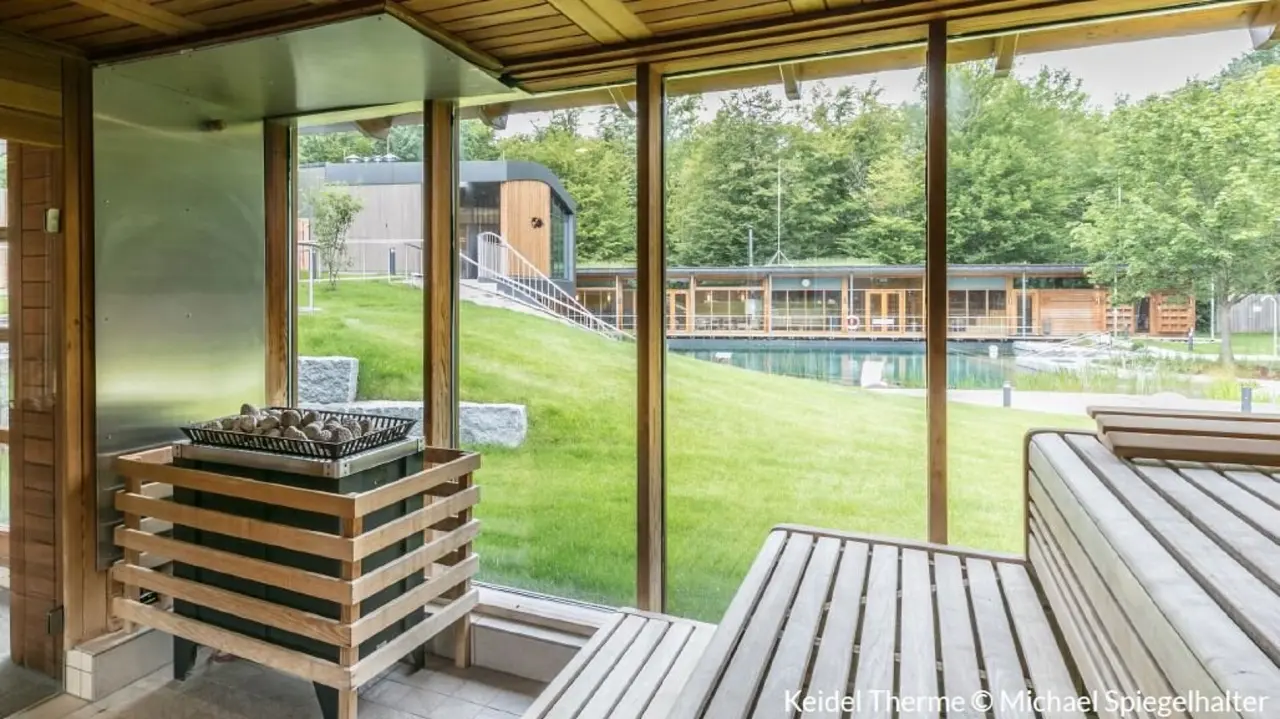Dorint An den Thermen in Freiburg-Süd – Sauna mit Blick auf die grüne Außenanlage und Pool | Wellnesshotel Schwarzwald