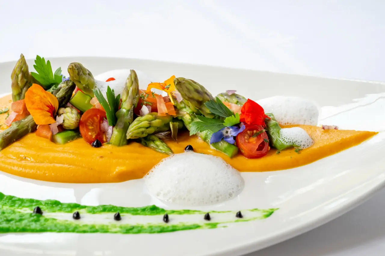 Kreatives Spargelgericht mit bunten Blüten und Saucen im Restaurant des Ringhotel Köhlers Forsthaus.