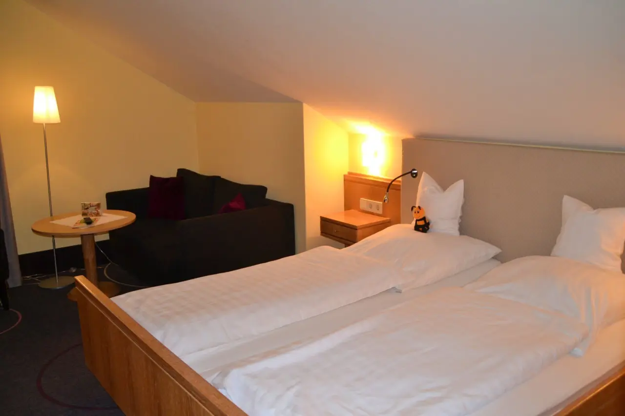 Gemütliches Doppelzimmer mit Dachschräge, zwei Einzelbetten und Sitzbereich im Ringhotel Köhlers Forsthaus.